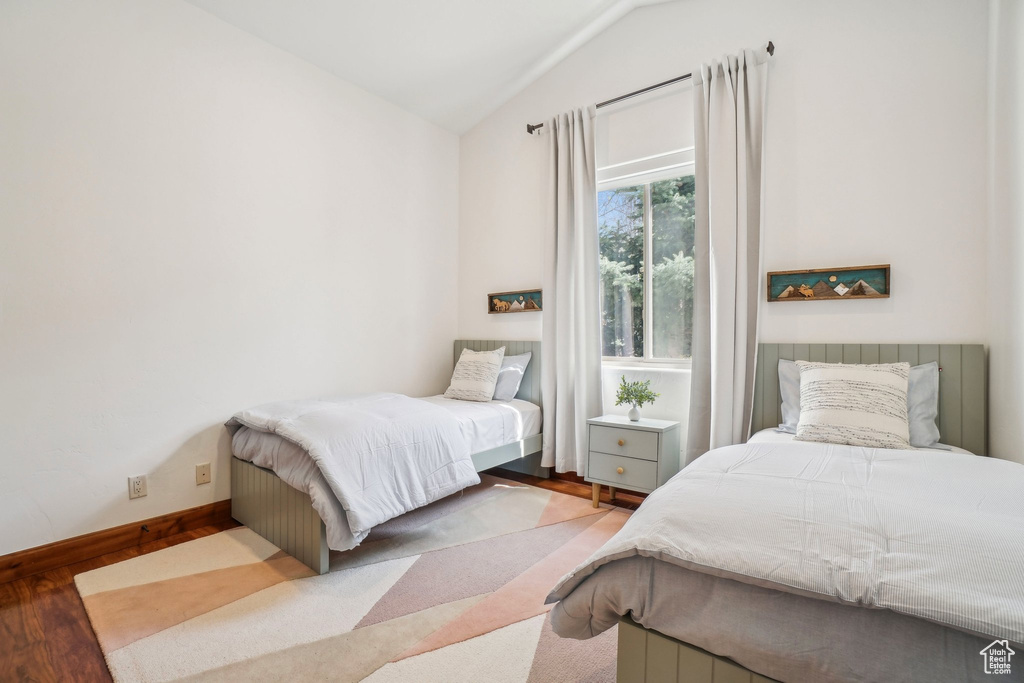 Bedroom featuring vaulted ceiling, baseboards, and wood finished floors