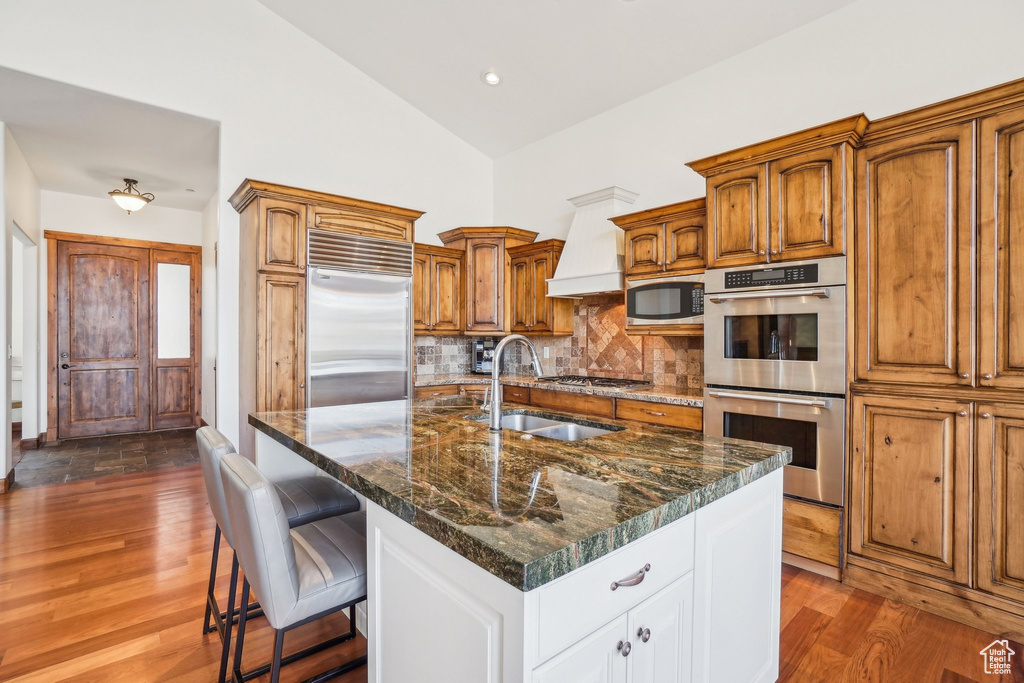Kitchen with high vaulted ceiling, a sink, dark wood finished floors, backsplash, and appliances with stainless steel finishes