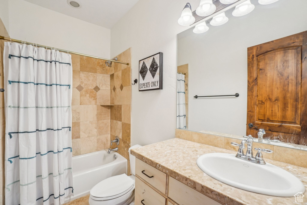 Bathroom with vanity, toilet, and shower / bath combination with curtain