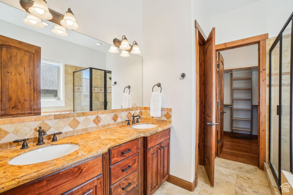 Bathroom with a sink, double vanity, decorative backsplash, and a shower stall