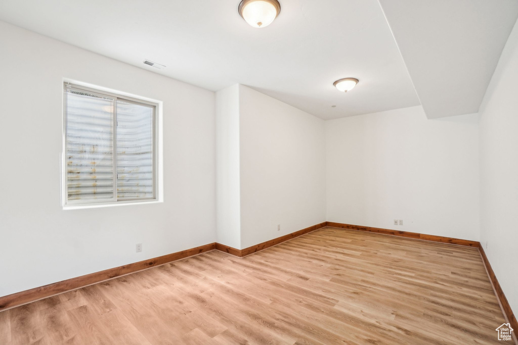 Unfurnished room featuring baseboards, visible vents, and light wood-style floors