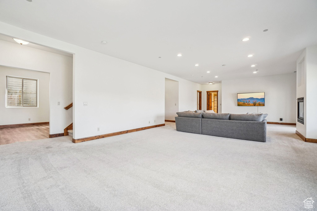 Living area featuring recessed lighting, light carpet, baseboards, and stairs