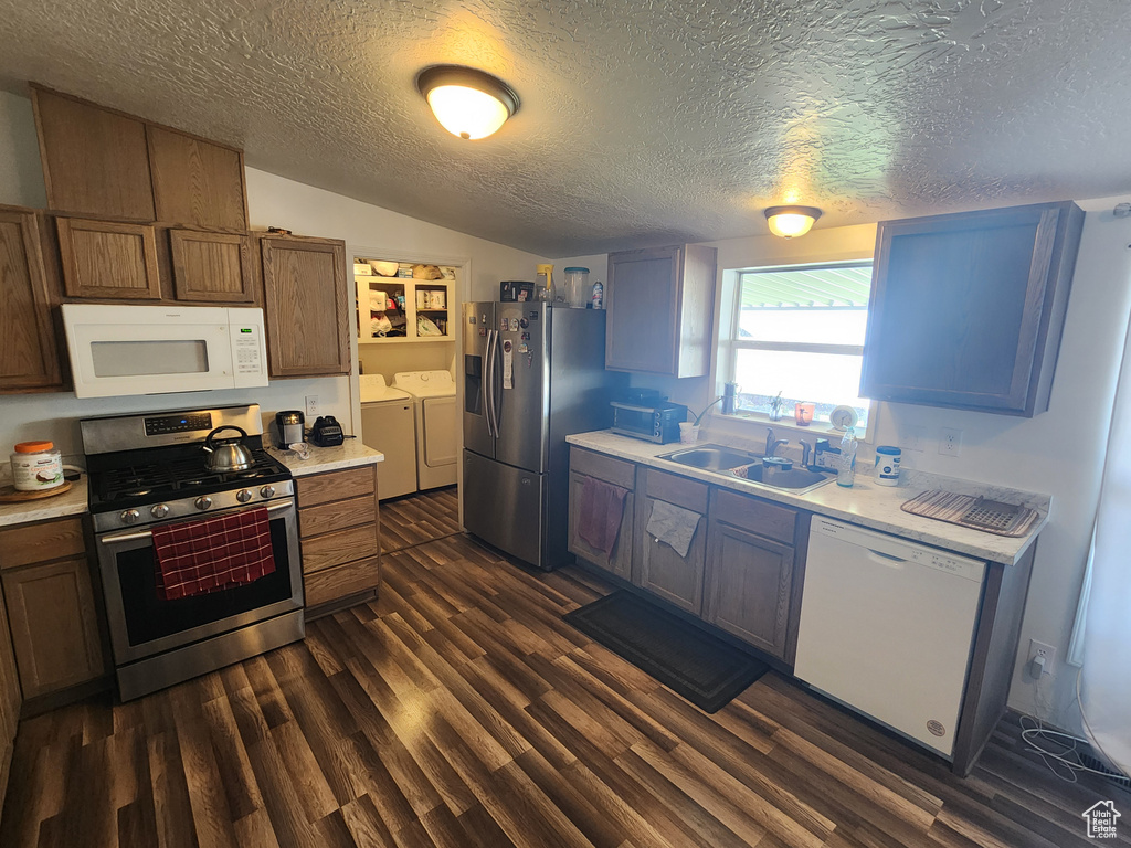 Kitchen featuring a sink, stainless steel appliances, a textured ceiling, light countertops, and washing machine and dryer