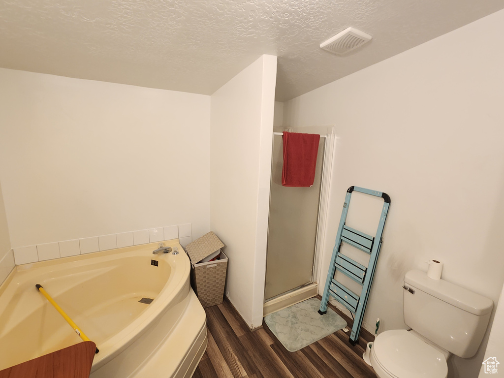 Bathroom featuring toilet, wood finished floors, a shower stall, and a textured ceiling