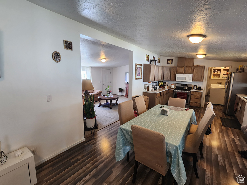 Dining space with baseboards, washer / clothes dryer, dark wood finished floors, and a textured ceiling