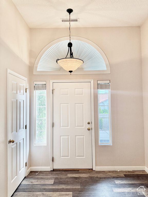Foyer entrance with baseboards, visible vents, and wood finished floors