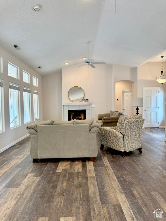 Living room with arched walkways, dark wood-style flooring, visible vents, and ceiling fan