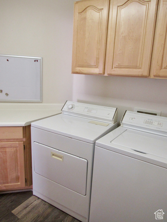 Laundry area with separate washer and dryer, cabinet space, and dark wood-type flooring