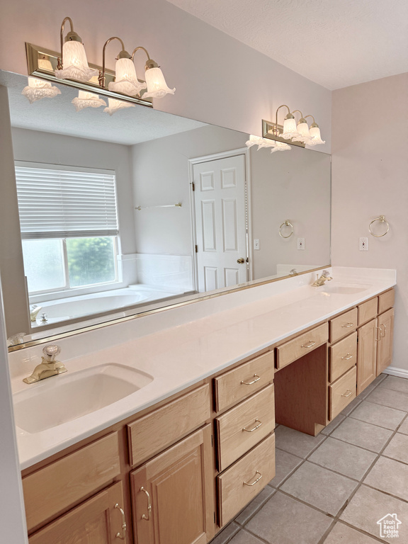 Bathroom with a sink, a bath, tile patterned flooring, and double vanity