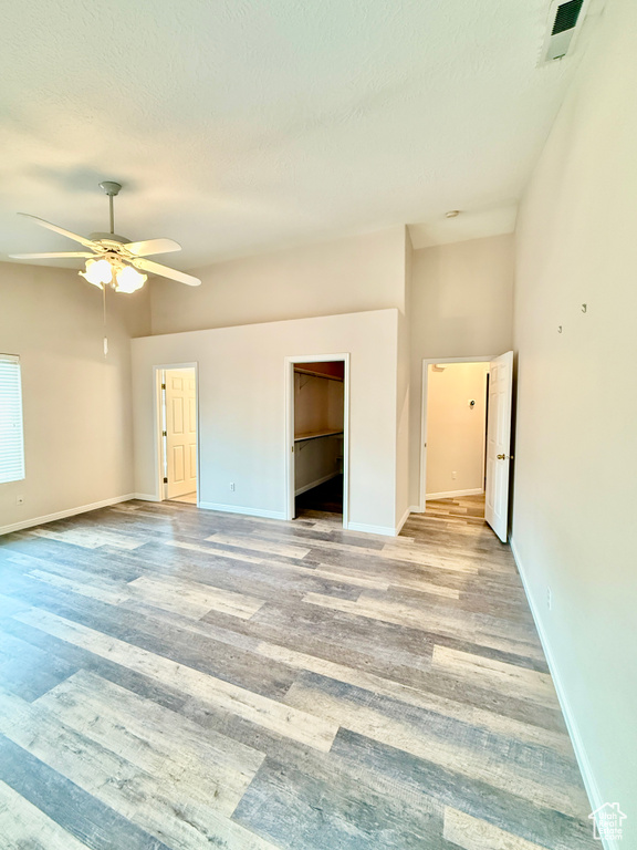 Empty room with visible vents, light wood-style flooring, baseboards, and ceiling fan
