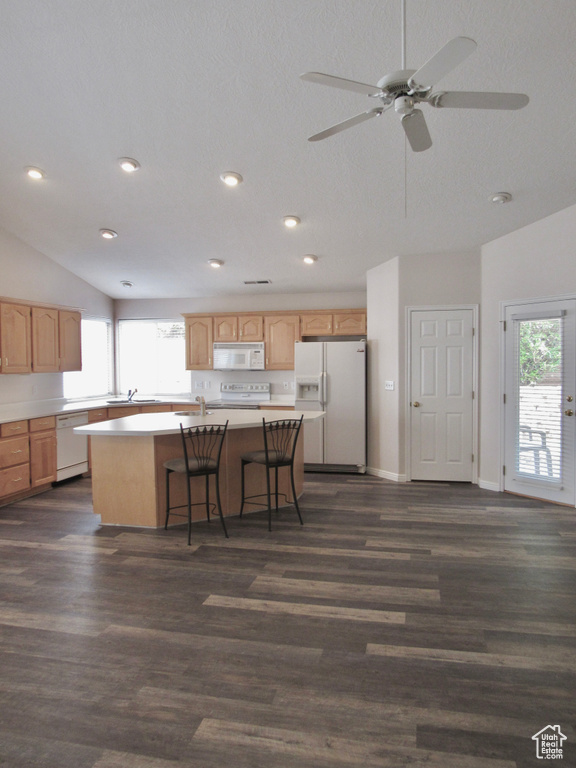 Kitchen with a center island, light countertops, lofted ceiling, light brown cabinets, and white appliances