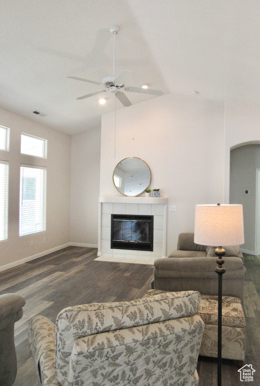 Living area featuring visible vents, wood finished floors, baseboards, a tile fireplace, and a ceiling fan
