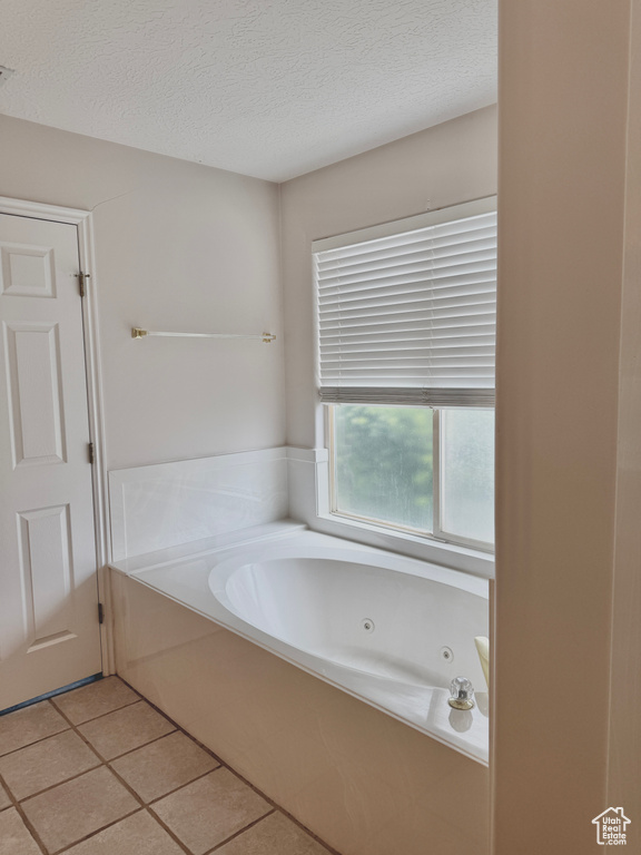Full bath featuring a whirlpool tub, a textured ceiling, and tile patterned floors