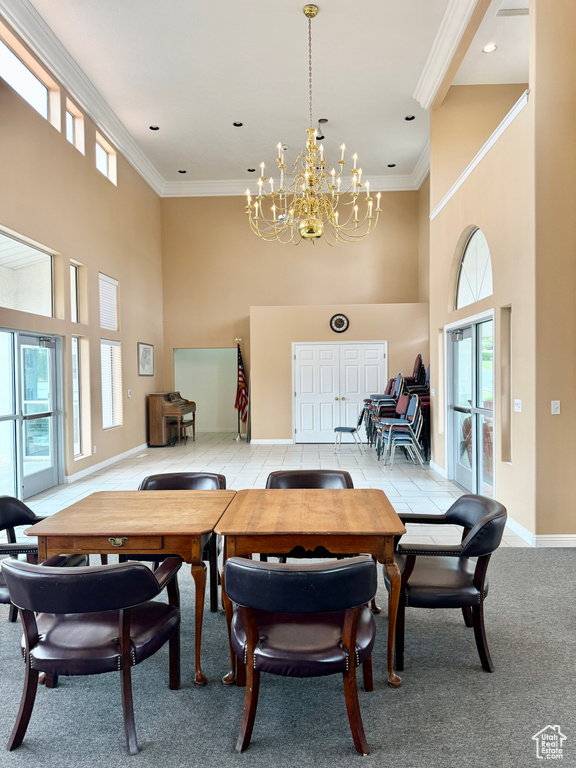 Dining room featuring ornamental molding, baseboards, light carpet, a high ceiling, and a notable chandelier
