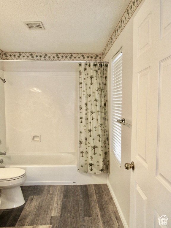 Full bathroom featuring visible vents, wood finished floors, toilet, and shower / bath combo with shower curtain