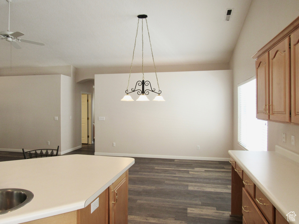 Kitchen with light countertops, hanging light fixtures, ceiling fan, and dark wood-type flooring