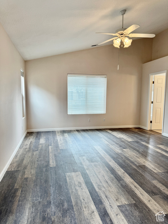 Empty room with a ceiling fan, baseboards, wood finished floors, and lofted ceiling