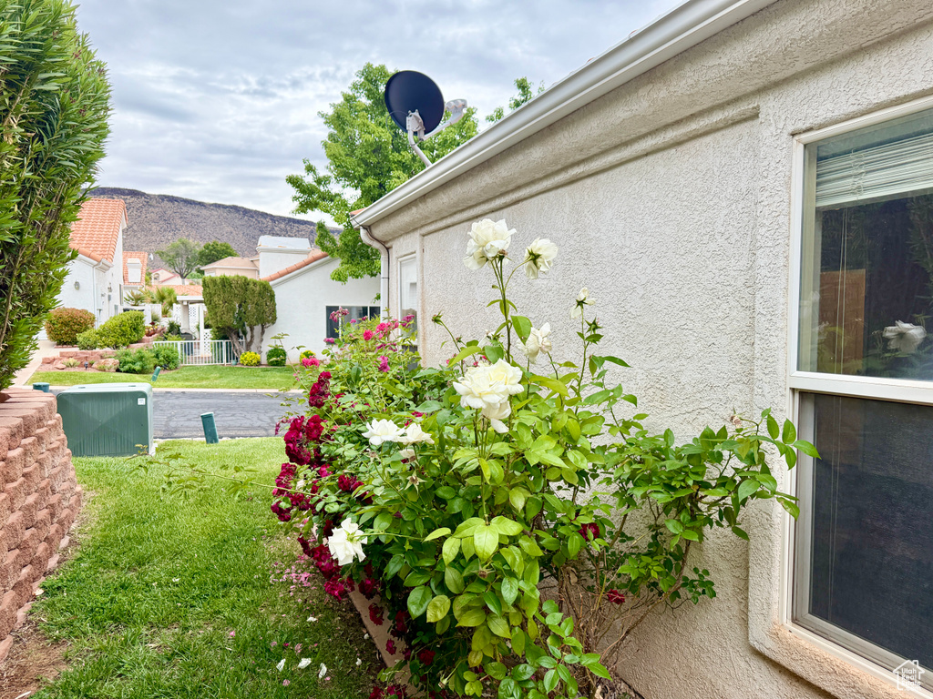View of home\'s exterior with stucco siding, a mountain view, and a lawn