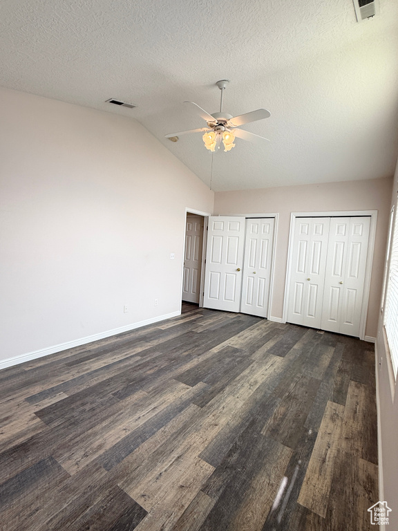 Unfurnished bedroom with visible vents, multiple closets, lofted ceiling, baseboards, and dark wood-type flooring