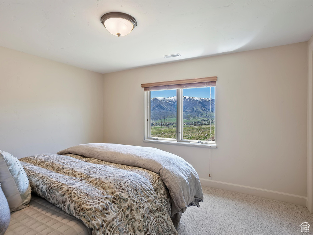 Bedroom with light colored carpet, baseboards, and visible vents
