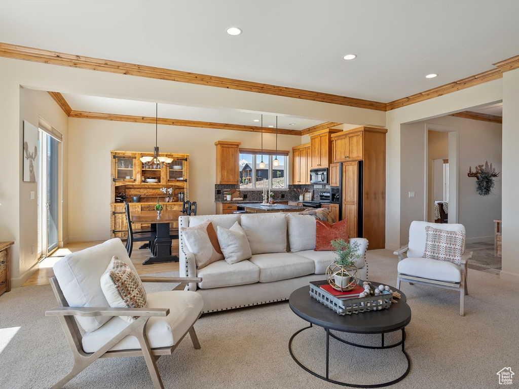 Living area featuring an inviting chandelier, baseboards, ornamental molding, and recessed lighting