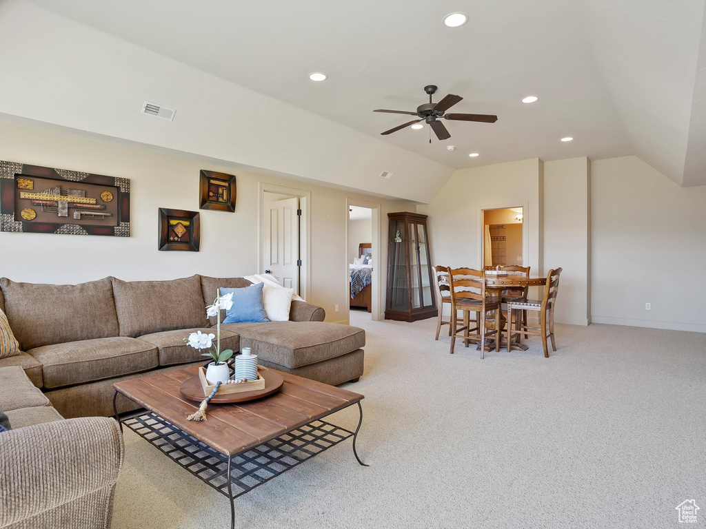 Carpeted living room with vaulted ceiling, ceiling fan, visible vents, and recessed lighting