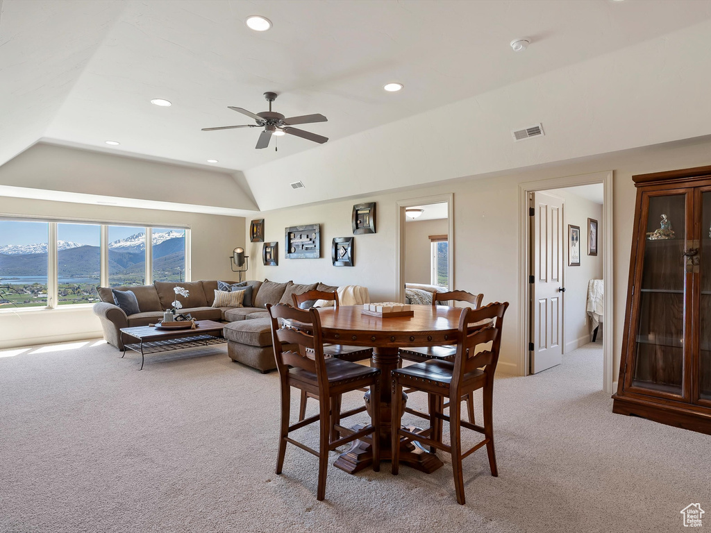 Dining area with a mountain view, a ceiling fan, visible vents, light carpet, and lofted ceiling