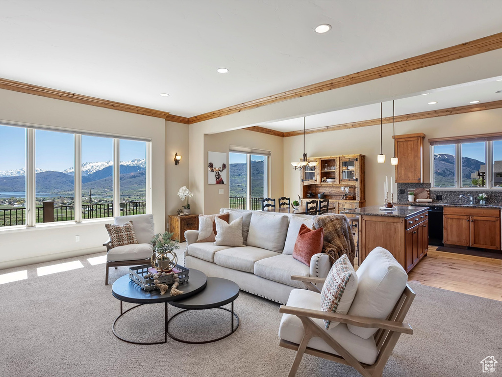 Living room featuring a mountain view, a notable chandelier, crown molding, light carpet, and recessed lighting