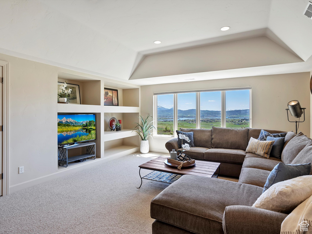 Living area with a raised ceiling, carpet flooring, recessed lighting, and built in shelves