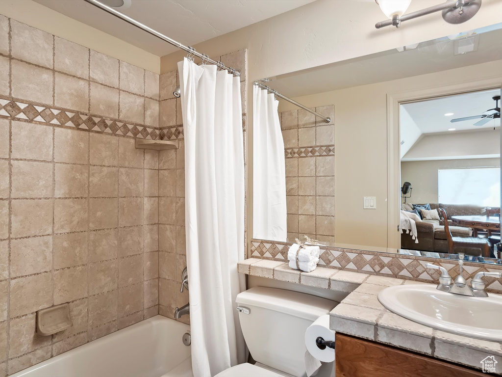 Full bathroom featuring toilet, shower / tub combo, ceiling fan, tasteful backsplash, and vanity