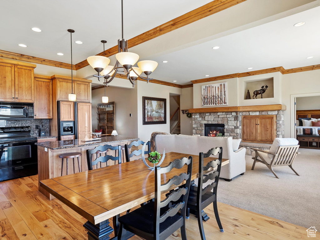 Dining space featuring crown molding, light wood-type flooring, a fireplace, and recessed lighting
