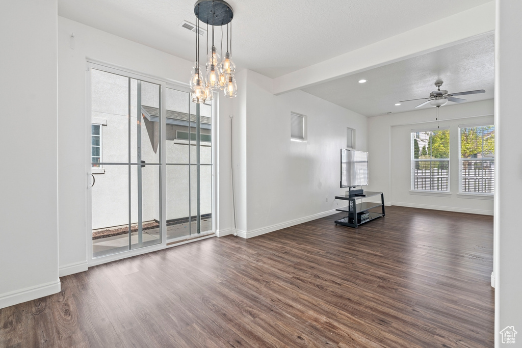 Unfurnished dining area with recessed lighting, baseboards, ceiling fan with notable chandelier, wood finished floors, and beam ceiling