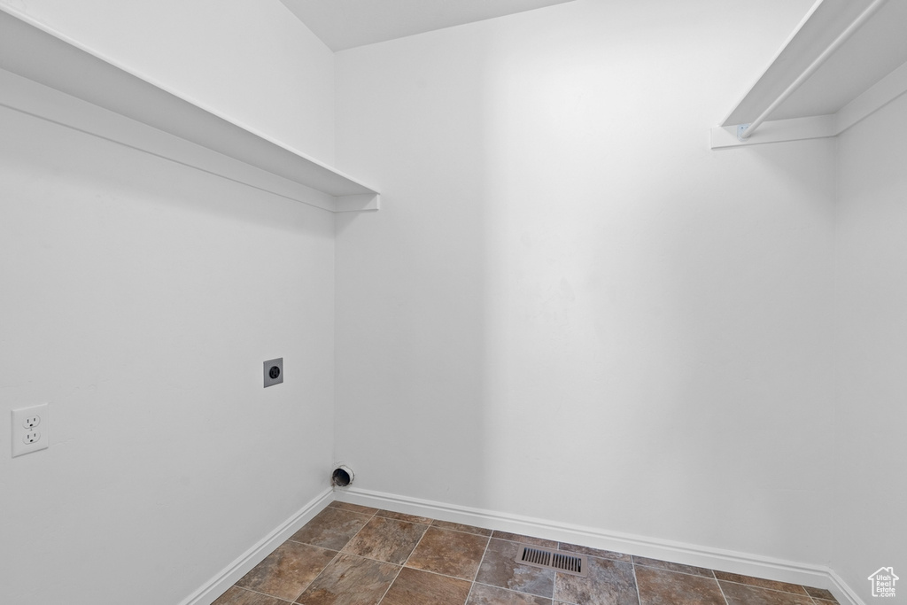 Clothes washing area with laundry area, stone finish floor, hookup for an electric dryer, visible vents, and baseboards