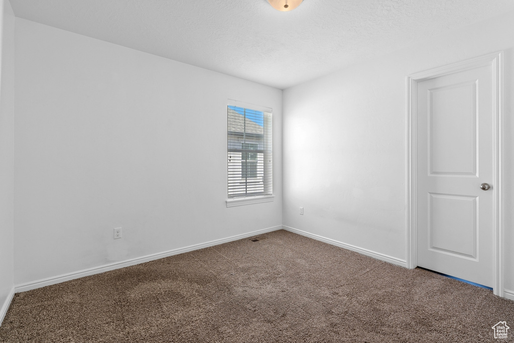 Unfurnished room with a textured ceiling, carpet floors, and baseboards