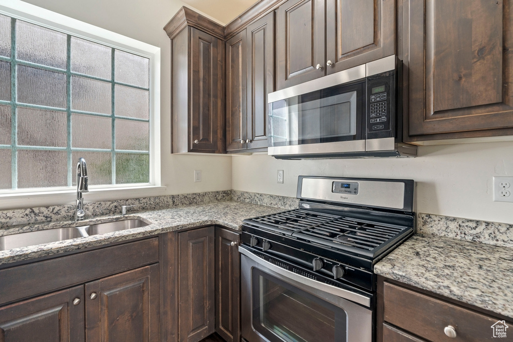 Kitchen featuring stainless steel appliances, dark brown cabinets, and a sink