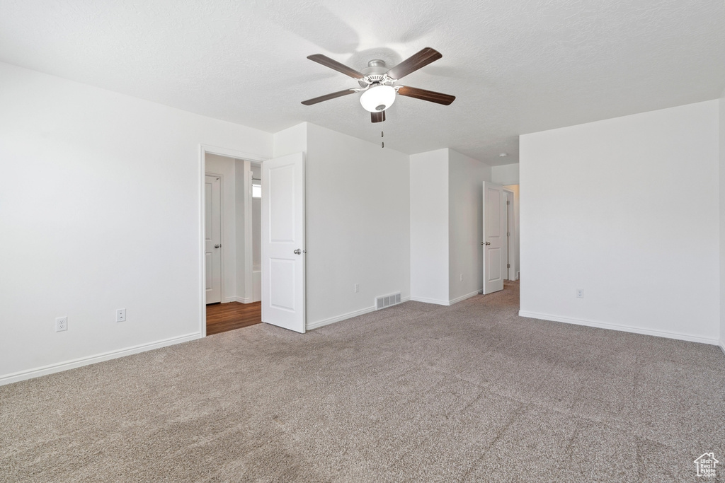 Carpeted spare room featuring baseboards, ceiling fan, and visible vents