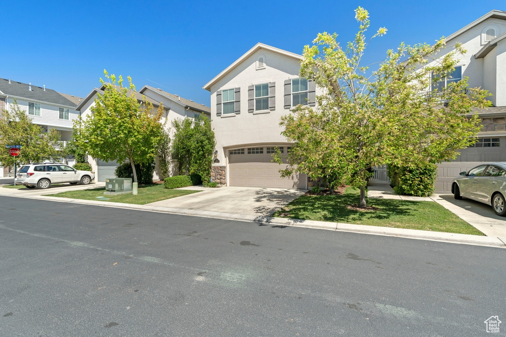 View of front of house with an attached garage, stone siding, a residential view, stucco siding, and driveway