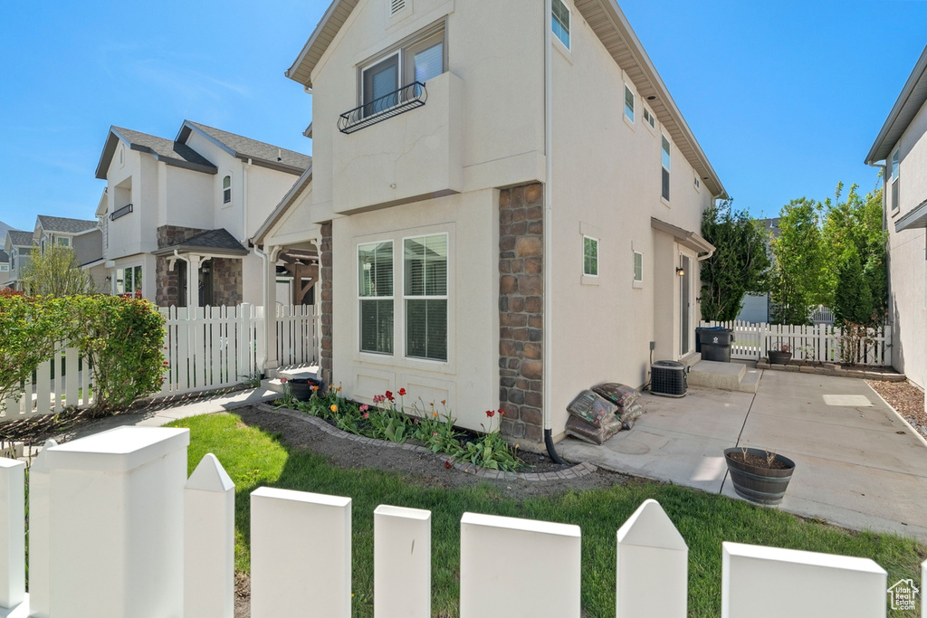 View of front of house with stone siding, stucco siding, fence, and a patio