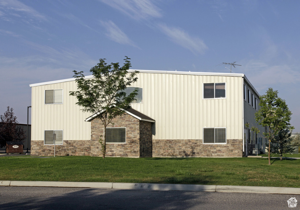 Exterior space featuring a yard, stone siding, and board and batten siding
