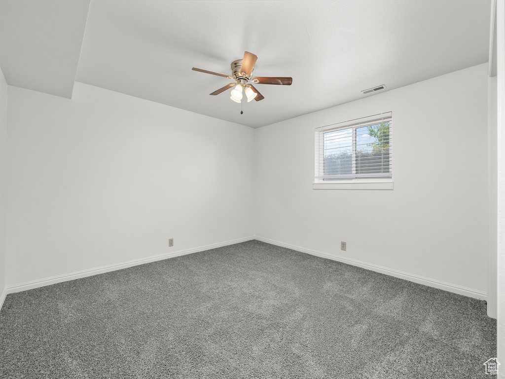 Carpeted empty room featuring baseboards, ceiling fan, and visible vents