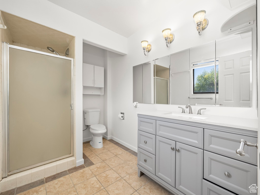 Full bath with vanity, toilet, tile patterned floors, baseboards, and a stall shower