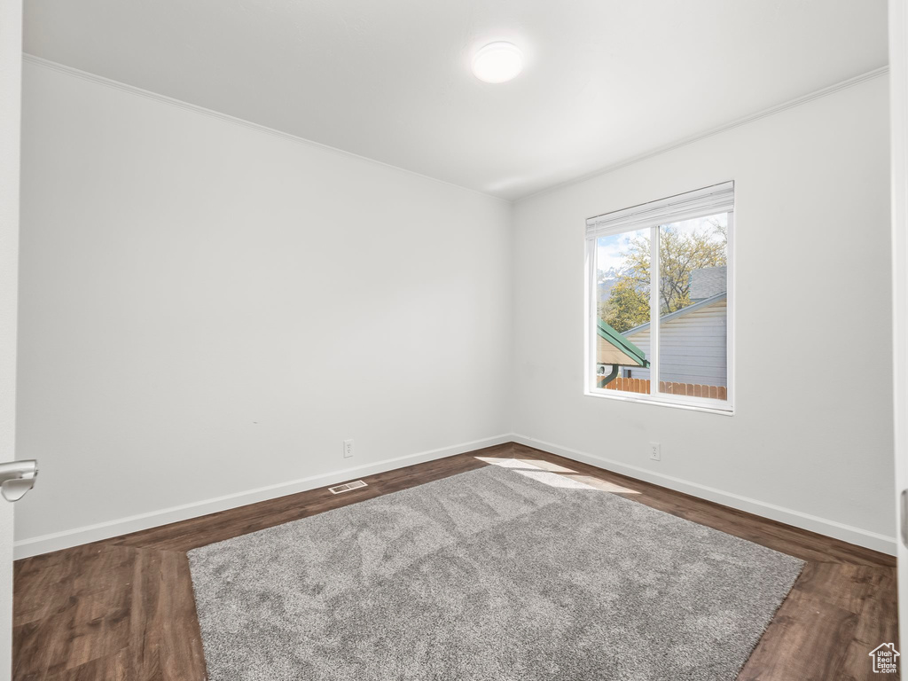 Spare room with baseboards, dark wood finished floors, and visible vents