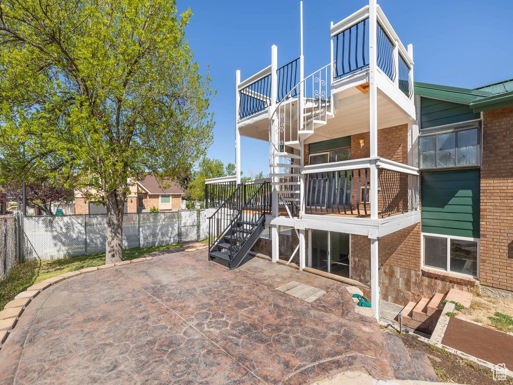 Rear view of house with fence, stairs, a patio, and brick siding