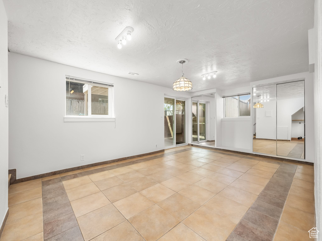 Unfurnished room featuring baseboards, a textured ceiling, an inviting chandelier, and light tile patterned floors