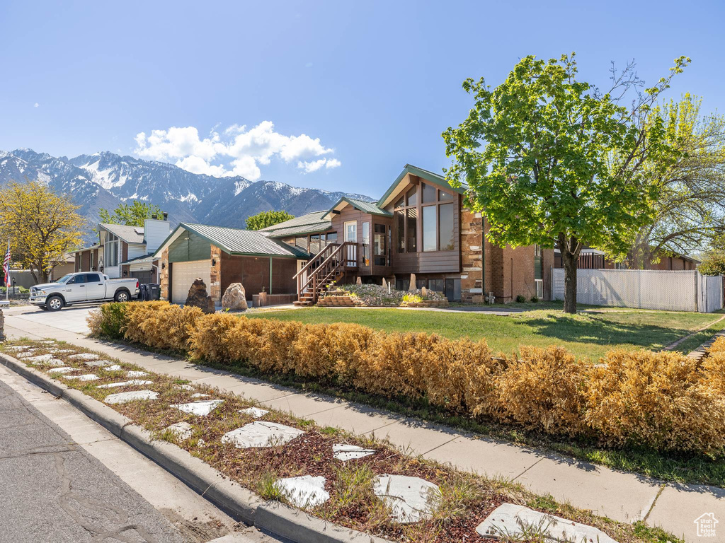 View of side of home featuring stairway, fence, a mountain view, a yard, and an attached garage