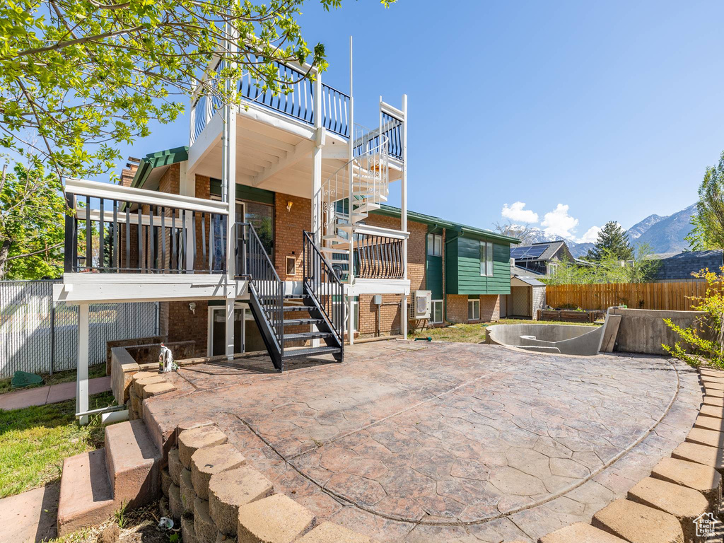 Back of house featuring fence, a patio, stairs, brick siding, and a mountain view