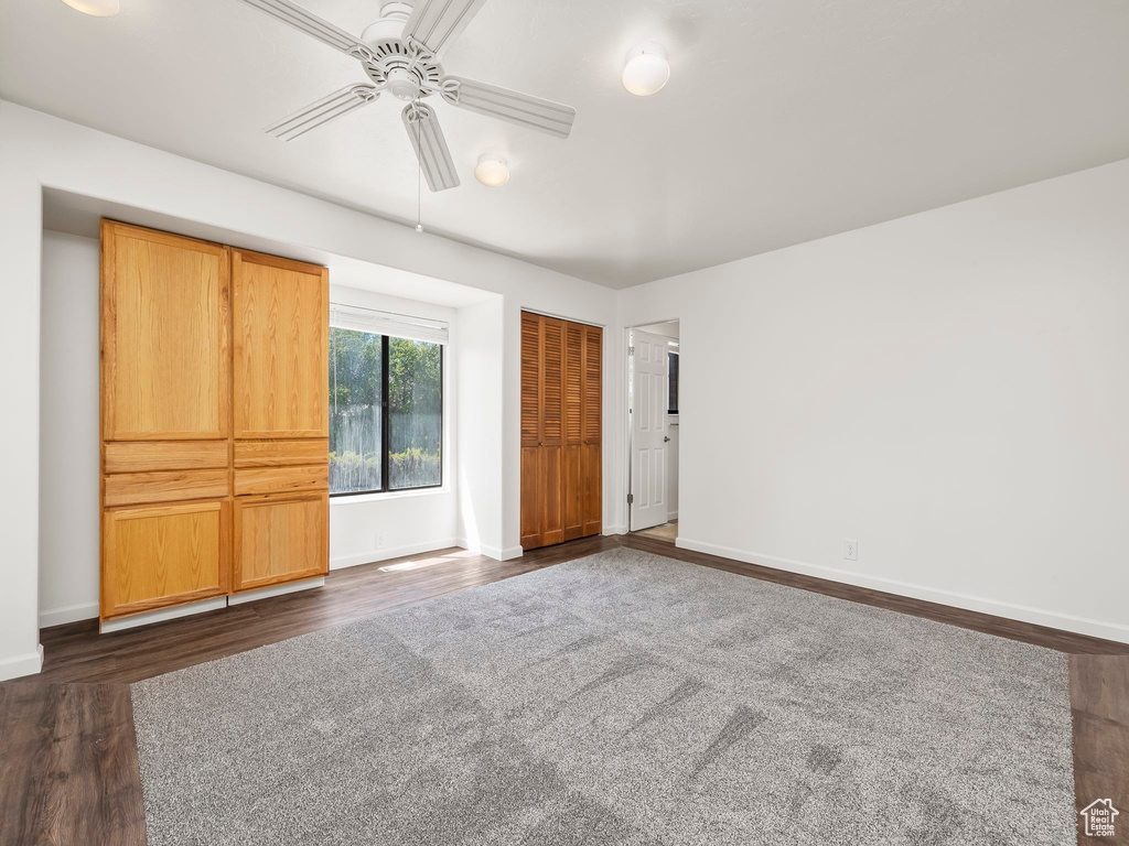 Unfurnished bedroom featuring baseboards, ceiling fan, a closet, and dark wood-type flooring