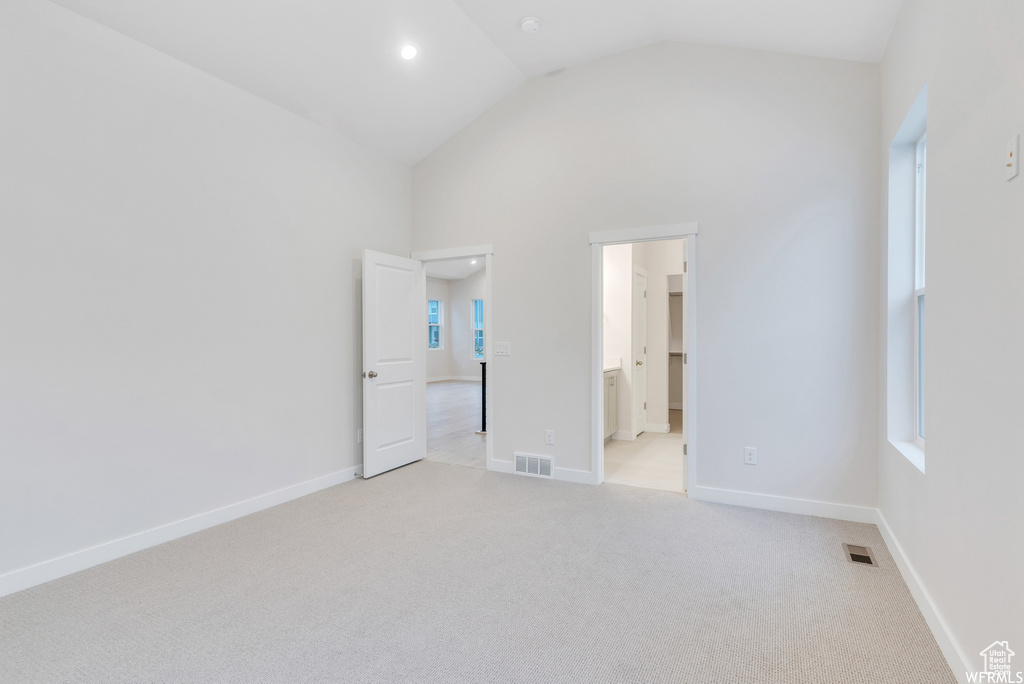 Unfurnished bedroom featuring light colored carpet, baseboards, high vaulted ceiling, and visible vents