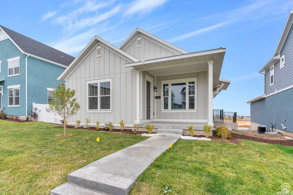 View of front of property with covered porch, board and batten siding, and a front lawn