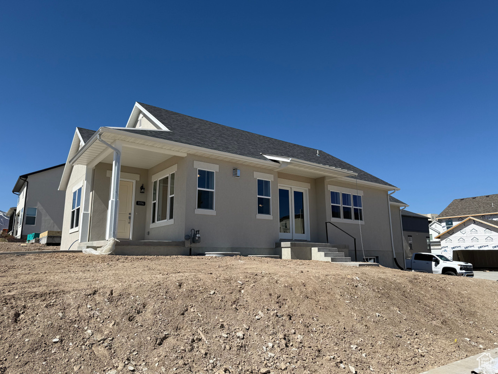 View of front of property featuring a shingled roof and stucco siding